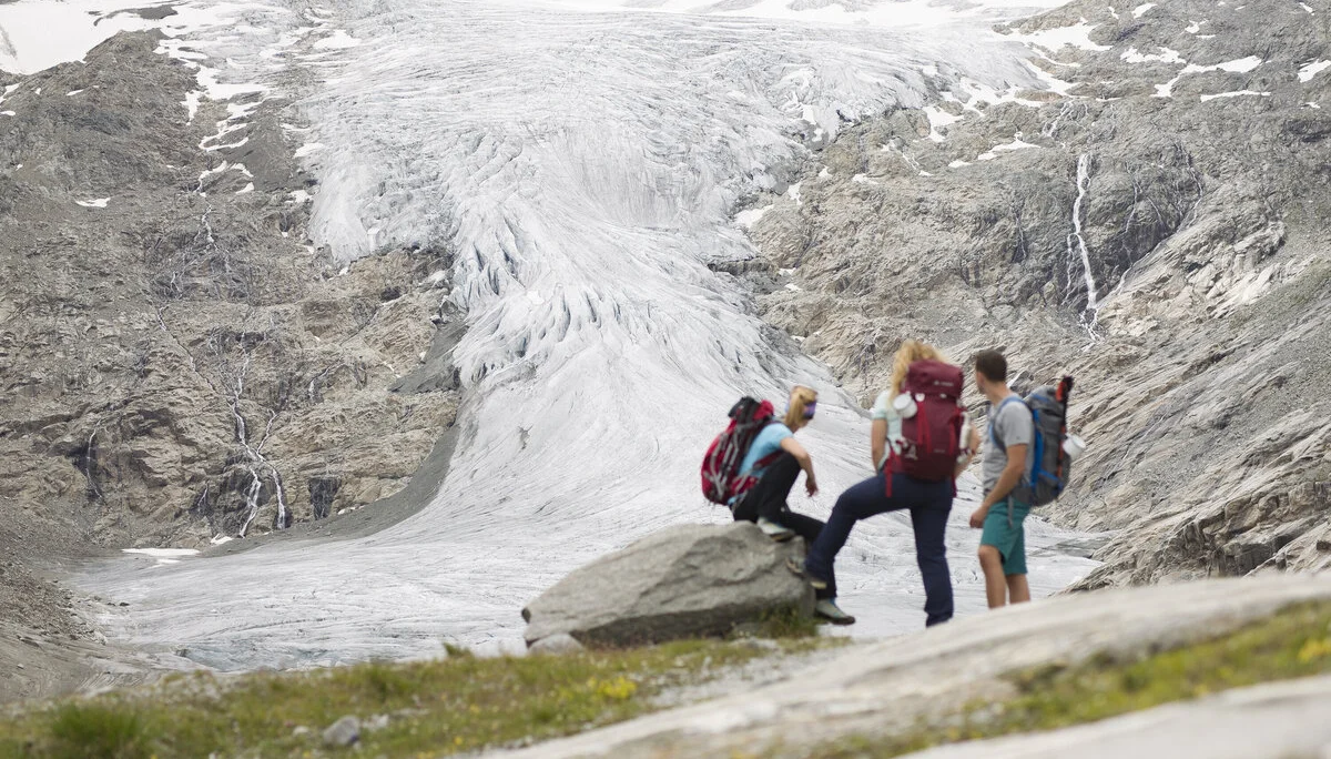 Drei Wandernde blicken nahe der Neuen Prager Hütte am Großvenediger auf den verschwindenden Gletscher. | © DAV / Jens Klatt